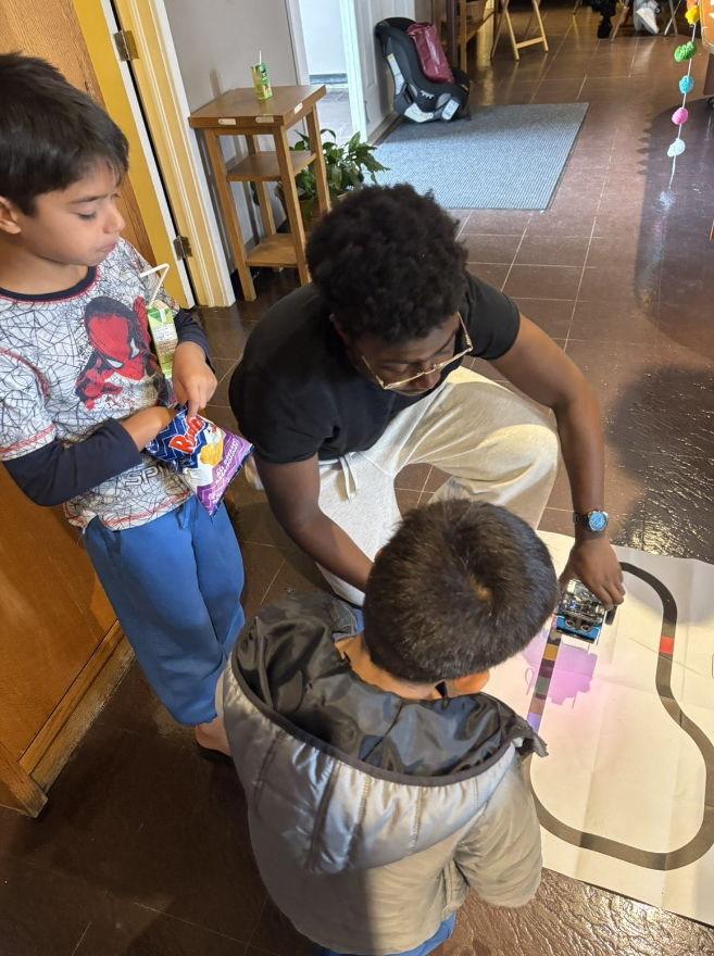 A mentor supporting children during a hands-on robotics activity