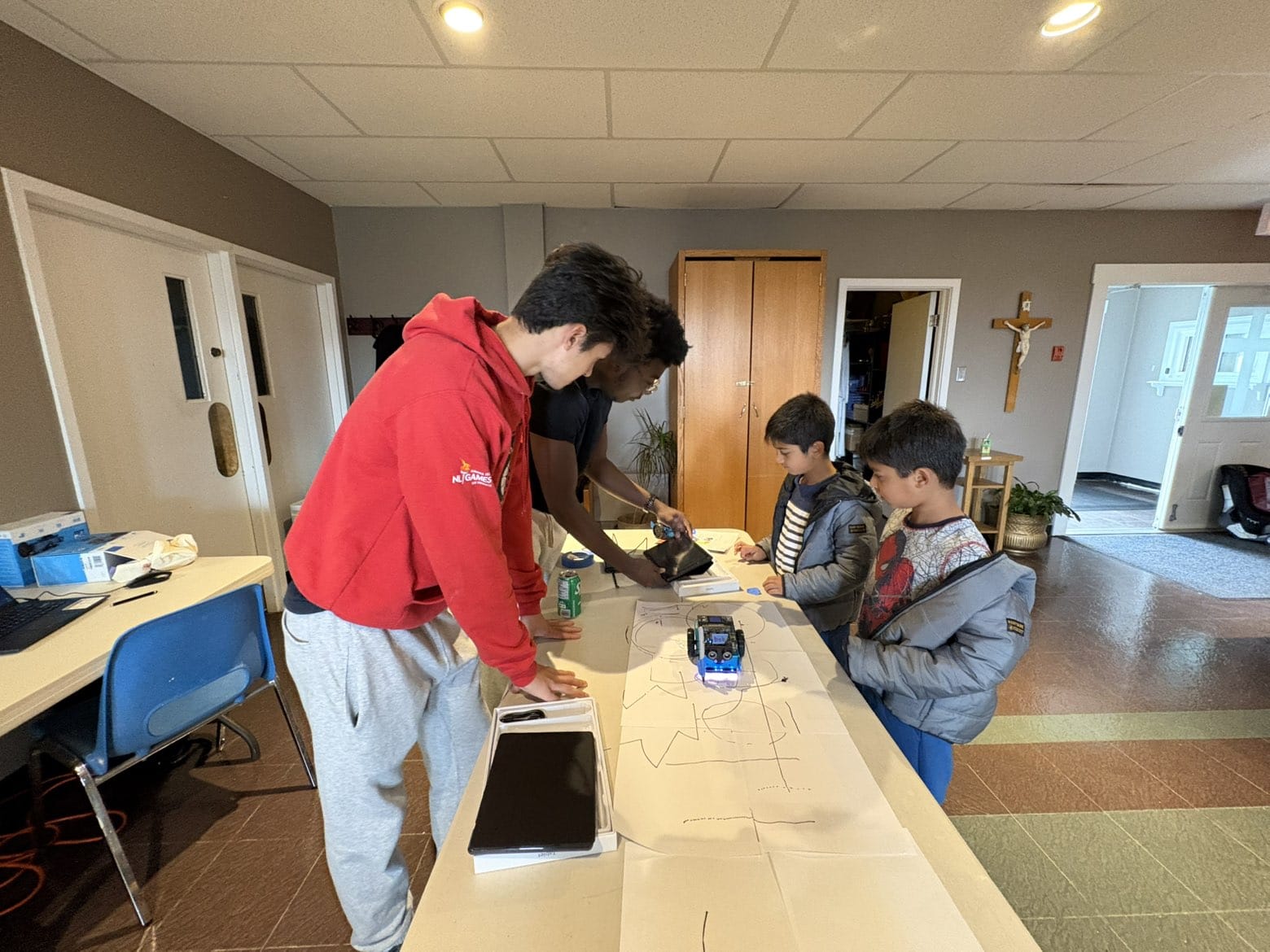 Young volunteers guiding children through a hands-on robotics activity